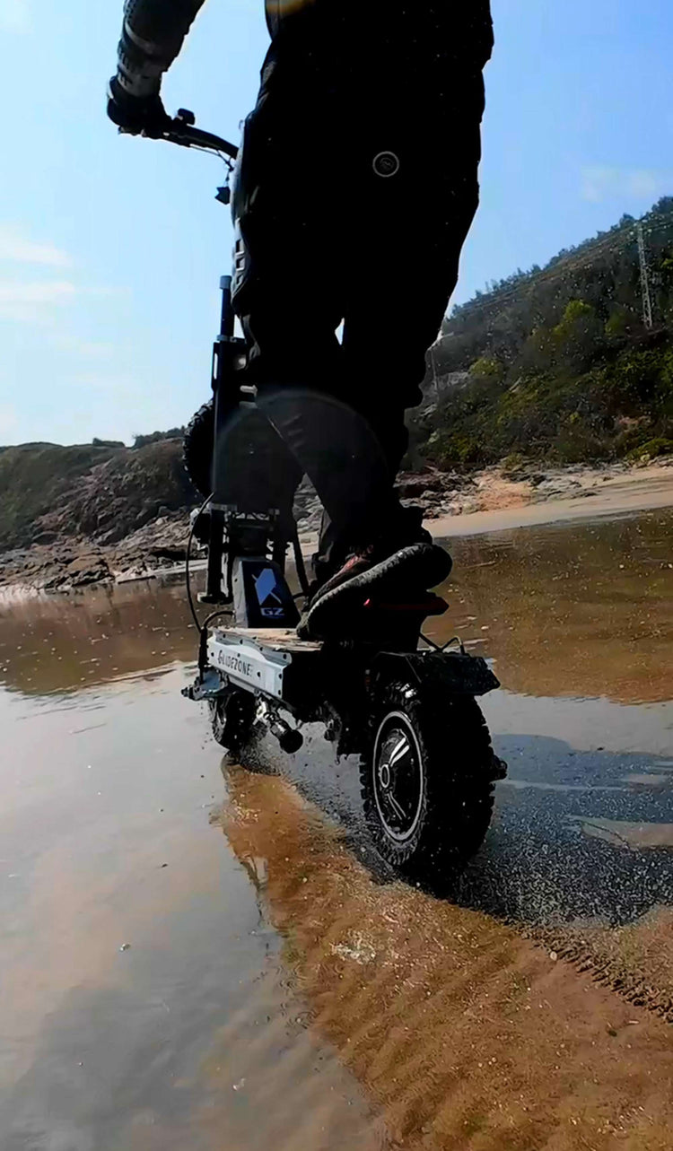 Close-up action shot of Glidezone GD83 riding on water with splashing waves, proving its waterproof capability.
