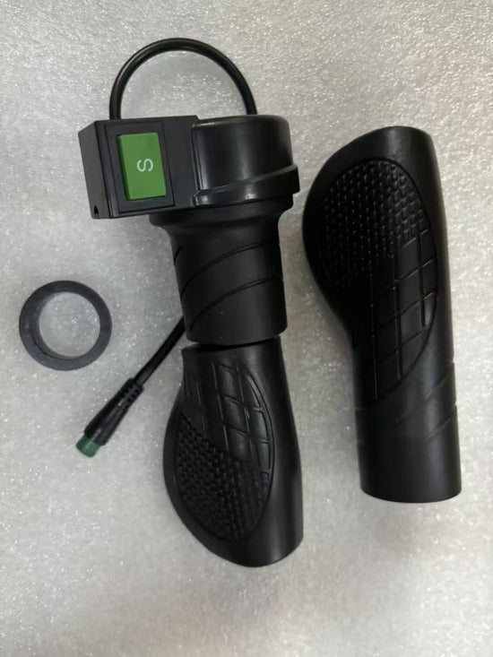 Replacement QNUT BK20 electric bicycle half-turn throttle handle featuring a textured non-slip rubber grip, a prominent green rocker switch labeled with an "S", a matching handlebar grip, a spacer ring, and a durable power cable with a green waterproof pin connector.