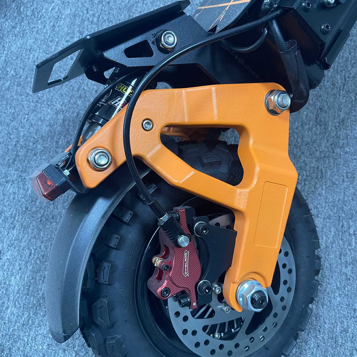 Orange right rear swing arm with a red hydraulic disc brake system on a Ronzlla RZ2 electric scooter