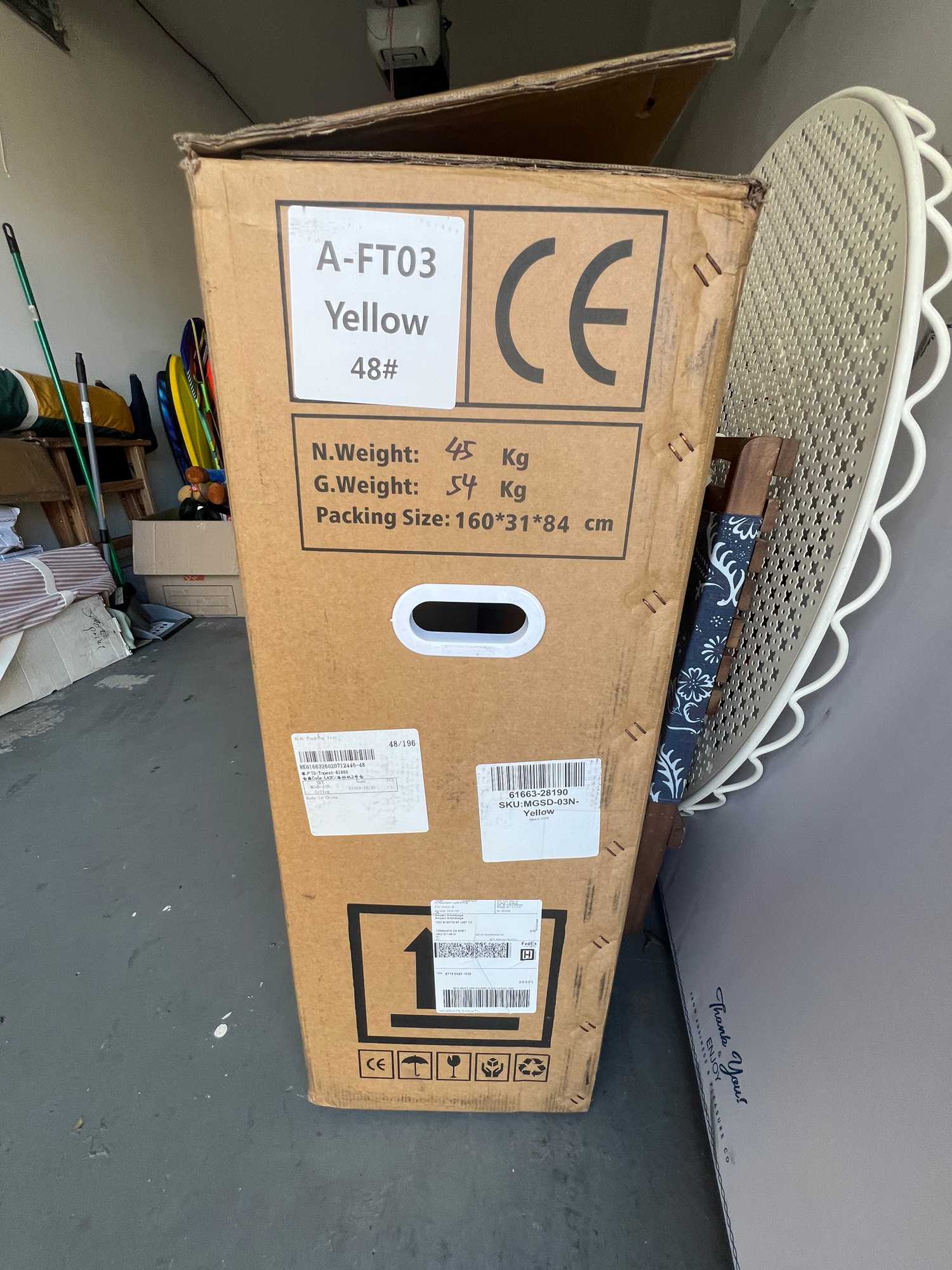 A large cardboard shipping box for a wholesale used electric bike in a US warehouse, showing technical specifications like a net weight of forty-five kilograms, gross weight of fifty-four kilograms, package size dimensions, and CE safety certification marks.